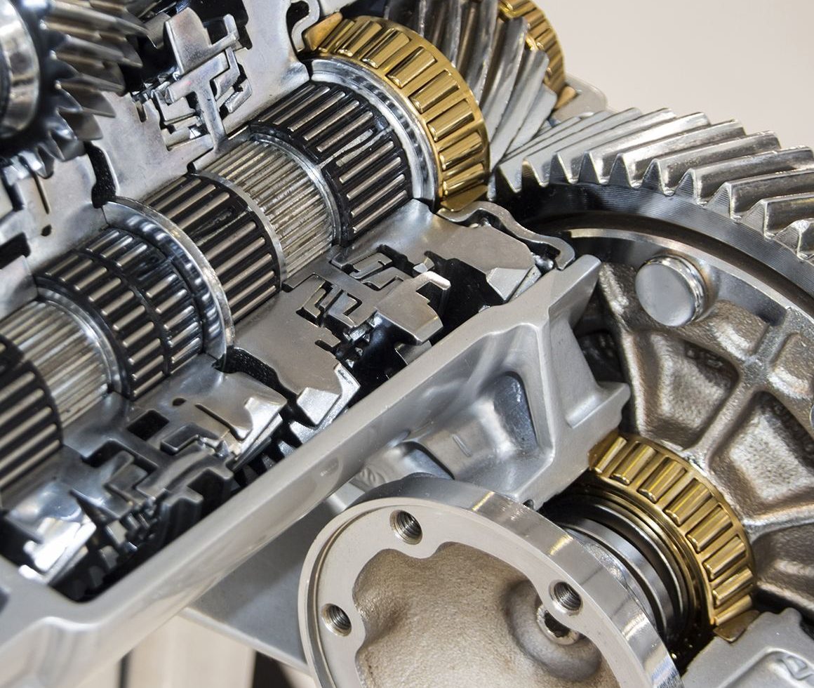 Close-up of a manual gearbox cutaway: shafts, needle bearings, brass synchro rings and the final drive gear
